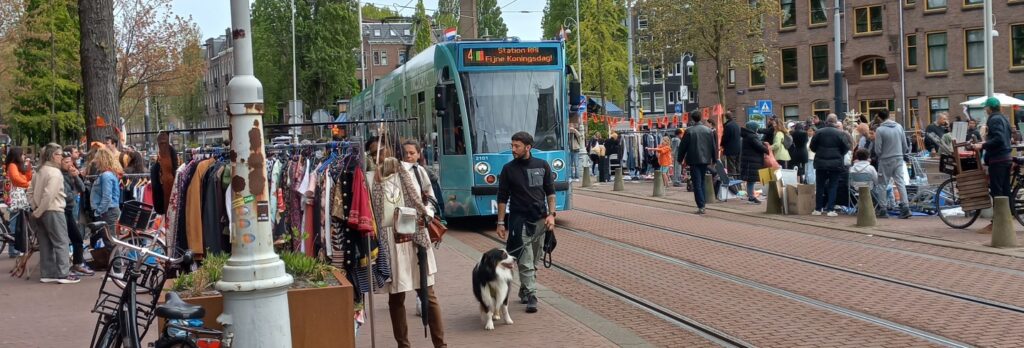 Een tram rijdt langs de vrijmarkt. Lijn 4. Fijne koningsdag